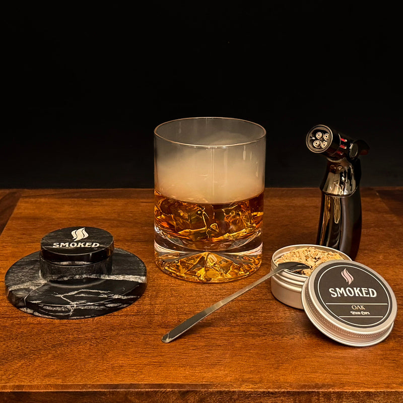 Glass of whiskey with smoked product packaging on a wooden surface