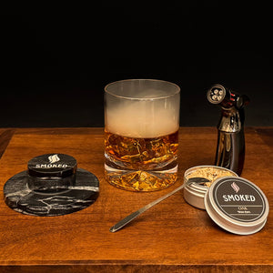 Glass of whiskey with smoked product packaging on a wooden surface